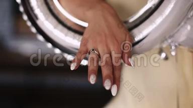 新娘在节日的银色气球里展示带有结婚戒指的手。